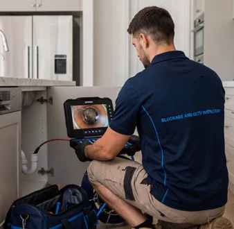 Plumber clearing a blocked toilet in a Chatswood bathroom